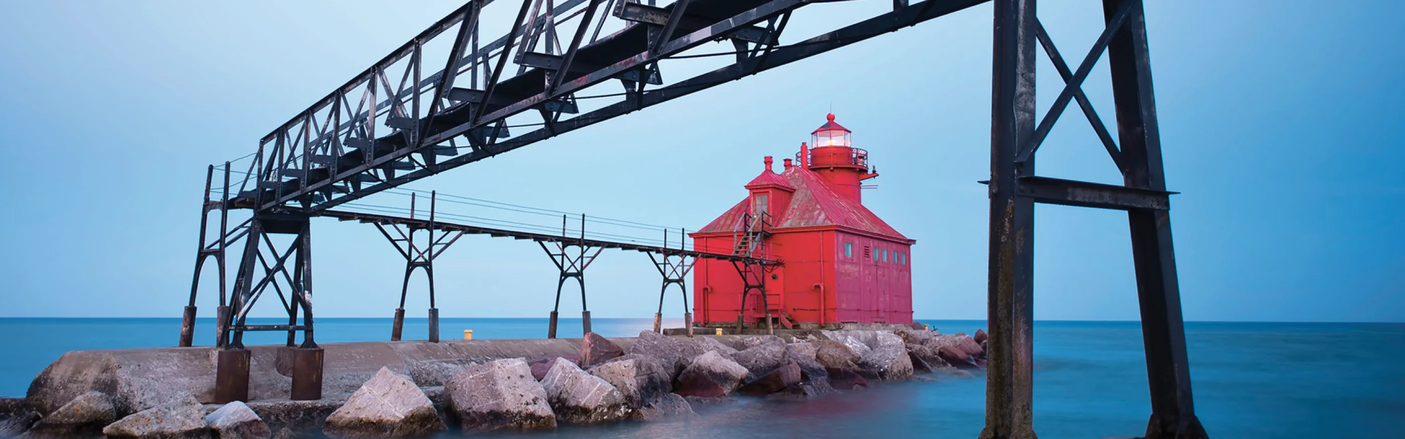 Roter Leuchtturm mit Brücke an einem schönen Morgen mit ruhiger See